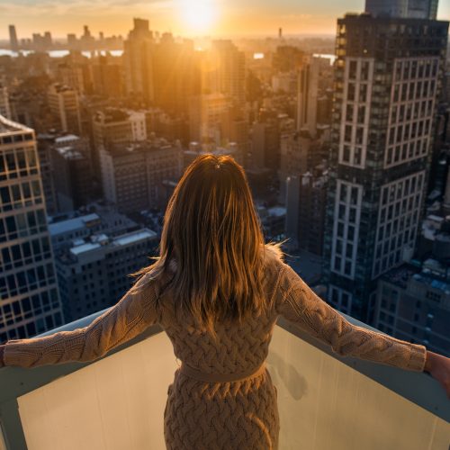 Rich woman enjoy the sunset standing on the balcony at luxury apartments in New York City. Luxury life concept. Succesful B
businesswoman relax.